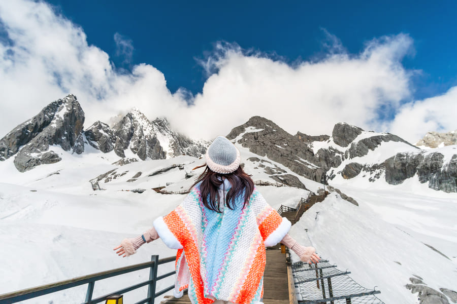 Viajera disfrutando de la Montaña Nevada del Dragón de Jade en Yunnan, China, un destino ideal para descubrir paisajes naturales y aventuras inolvidables.